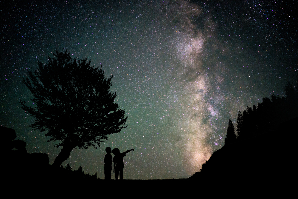Silhouette two little boys with Milky Way and beautiful night sky full of stars in background